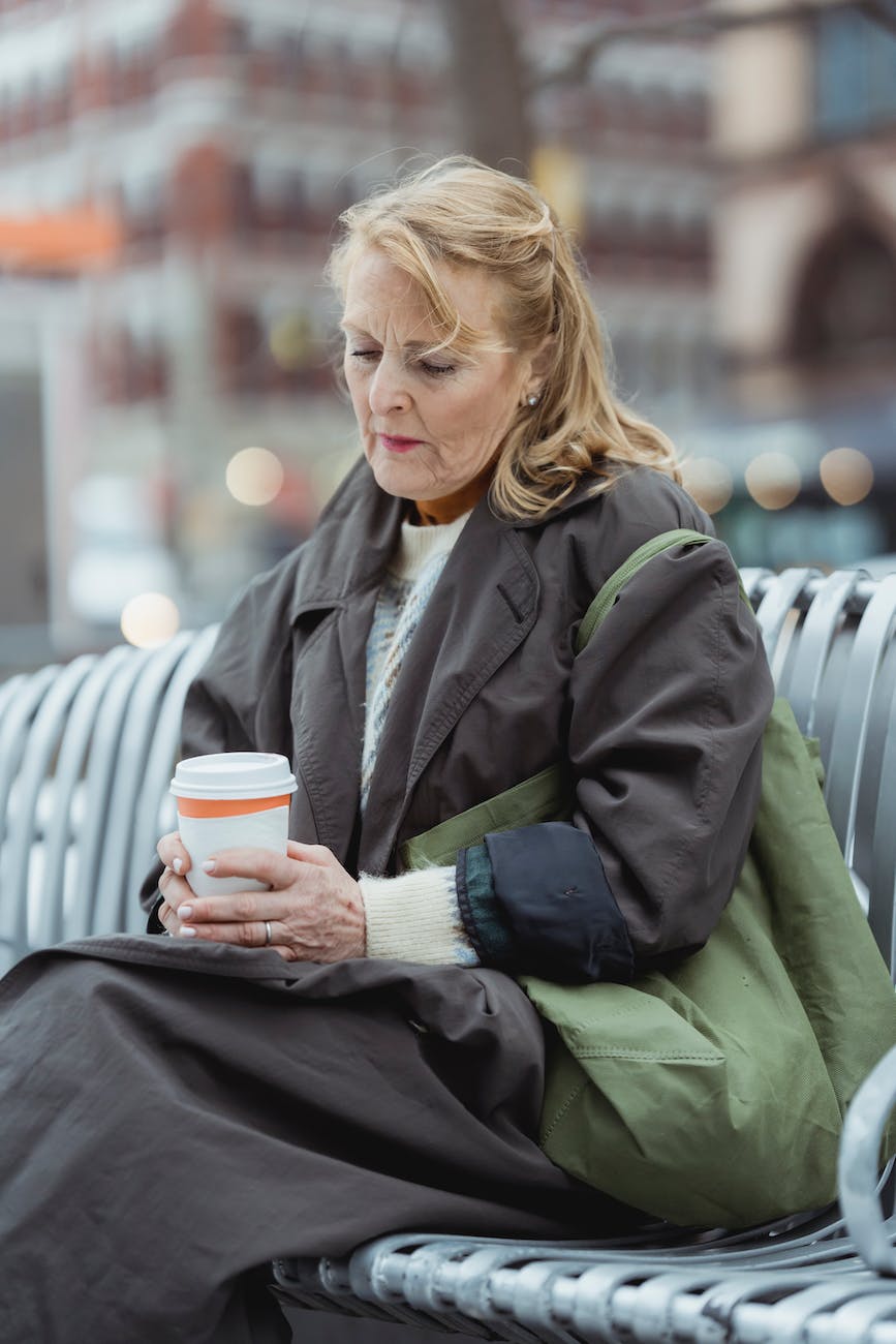 senior woman with coffee to go on urban bench