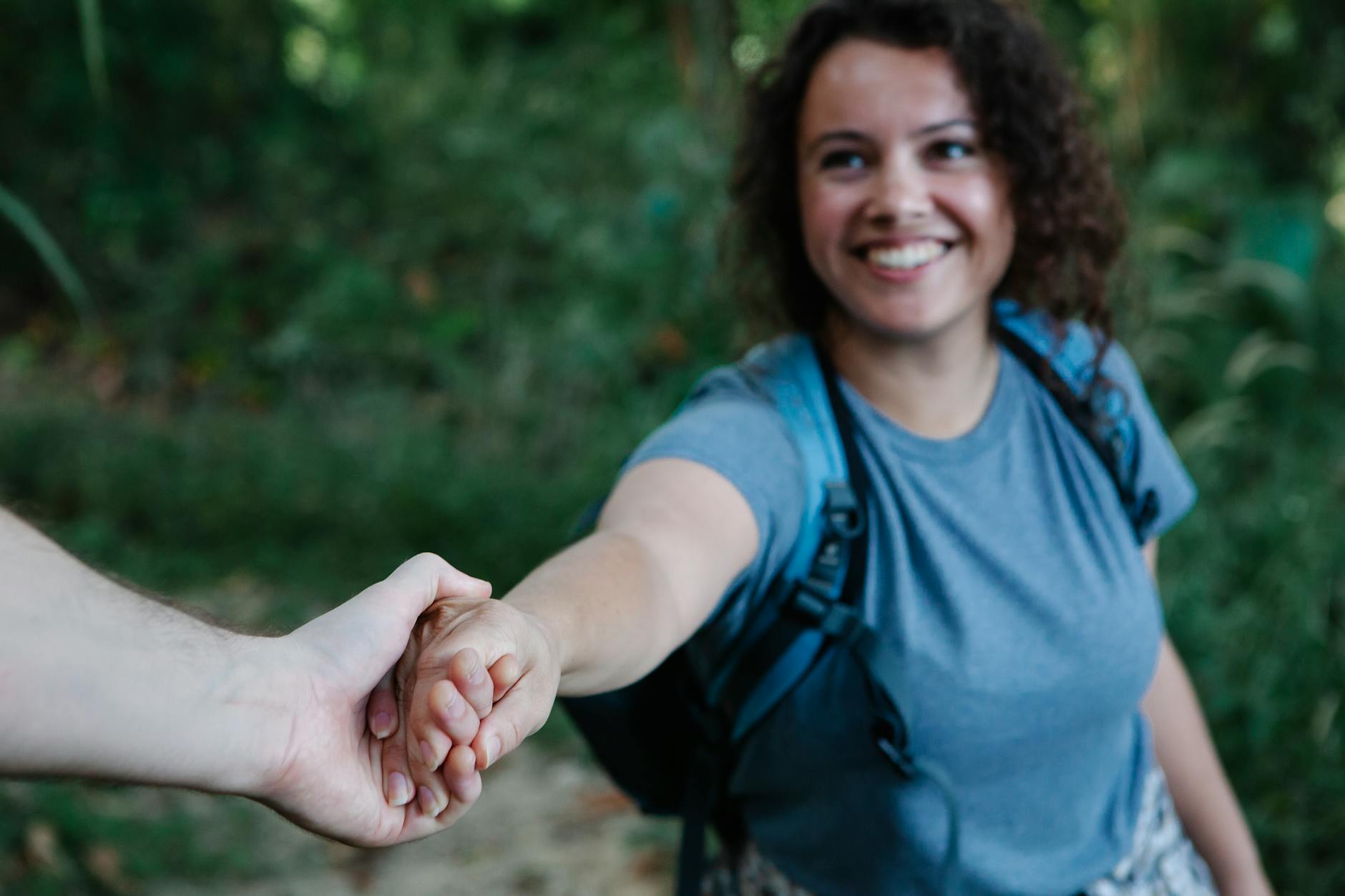 crop cheerful backpacker holding hand of boyfriend during hike